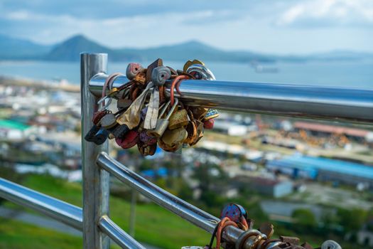 Metal fence with locks on a blurry background of the city landscape. Nakhodka, Russia