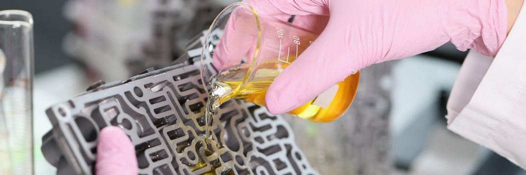 Close-up of mechanic man pouring liquid purified oil on automobile part. Lubricating liquid in glass flask, repair car detail. Pit stop, testing concept