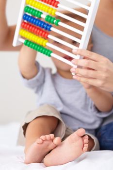 Learning to count. A mother and her toddler son counting on an abacus
