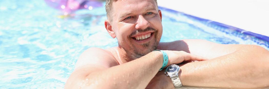 Portrait of middle aged man chill in swimming pool on summer holiday. Happy person on hotel territory. Summer, resort, leisure, trip, relaxation concept