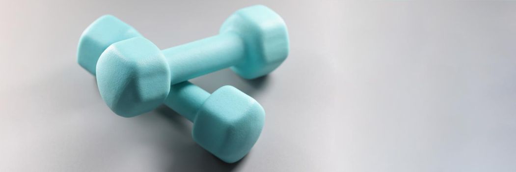Close-up of pair of blue dumbbells on grey surface, planning weight loss, equipment for sport activity. Sport, health, physical activity, habit concept