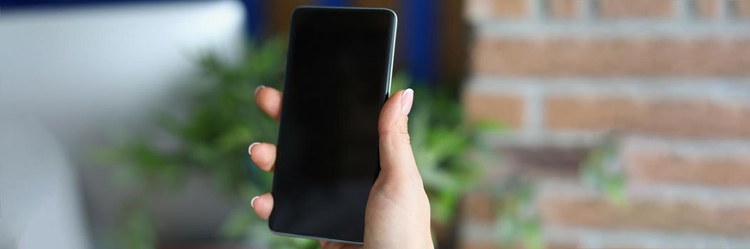 Close-up of woman hold in hand smartphone with black screen, turn off mobile phone. Locked device screen in hand. Mockup, technology concept. Copy space