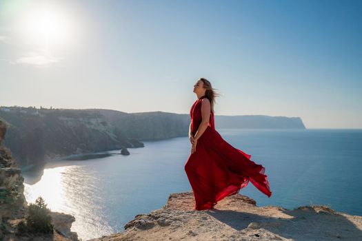 A woman in a red flying dress fluttering in the wind, against the backdrop of the sea