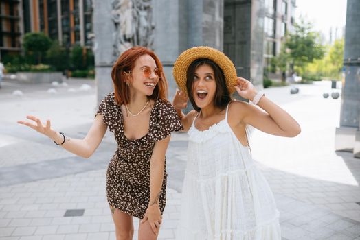 Portrait of two young beautiful smiling hipster female in trendy summer clothes.Sexy carefree women posing on street background.