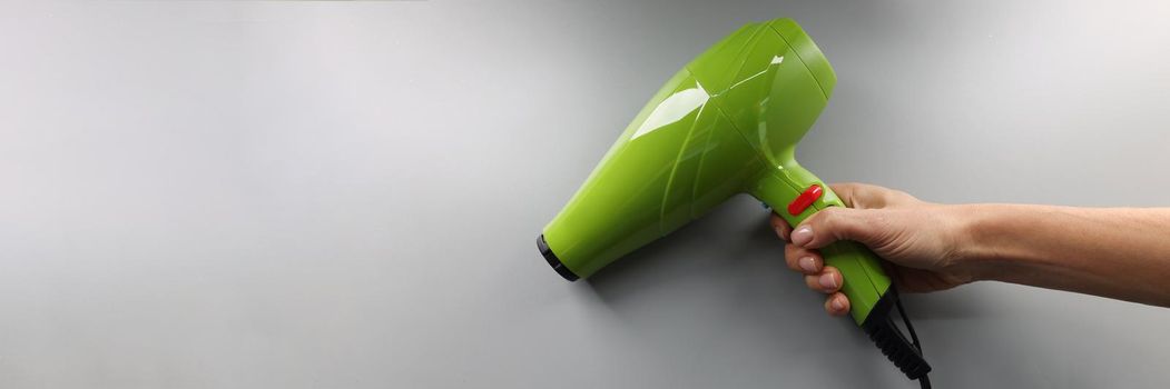 Top view of brand new hairdryer model, bright green device for drying hair in hand. Necessary modern equipment for master in beauty salon. Tool concept