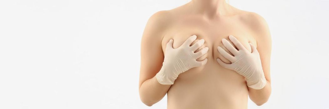 Portrait of female cover breasts with hands, natural size of boobs, white background. Enlarge breasts, beauty procedure. Plastic, cosmetic surgery concept