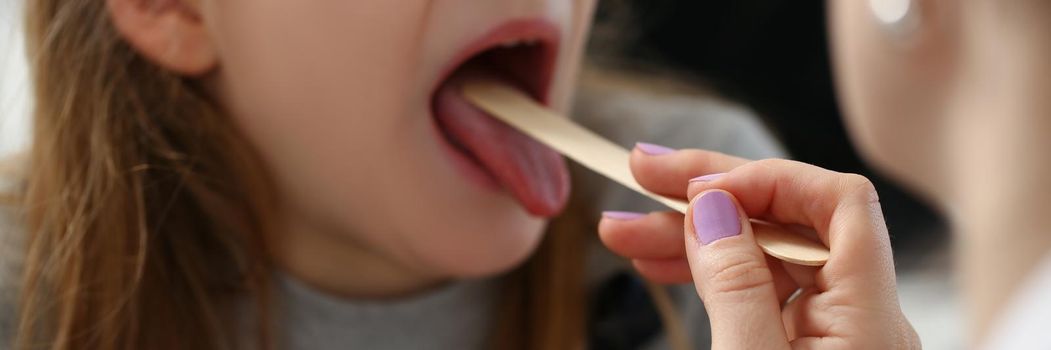 Portrait of girl open mouth for check up, hurting throat, pediatrician check with stick. Female doctor use tool for examination health. Medicine concept