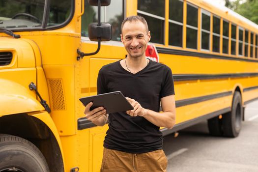 handsome teacher looking at camera school bus blurred on background.