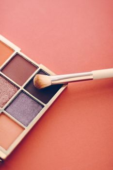 Cosmetic branding, mua and girly concept - Eyeshadow palette and make-up brush on orange background, eye shadows cosmetics product as luxury beauty brand promotion and holiday fashion blog design