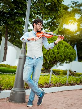 Man playing violin in the street. Portrait of man playing violin in the street. Jacket artist playing violin outdoors, Image of a person playing violin outdoors