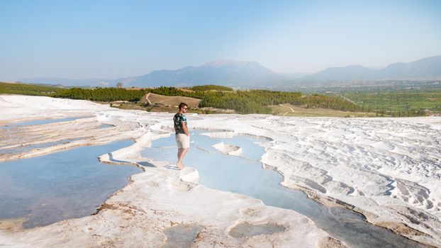 Natural travertine pools and terraces in Pamukkale. Cotton castle in southwestern Turkey,young men watching sunset at the natural pool Pamukkale Turkey