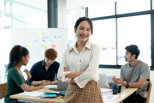 Attractive young asian woman standing confident in the office in front of her team in meeting room