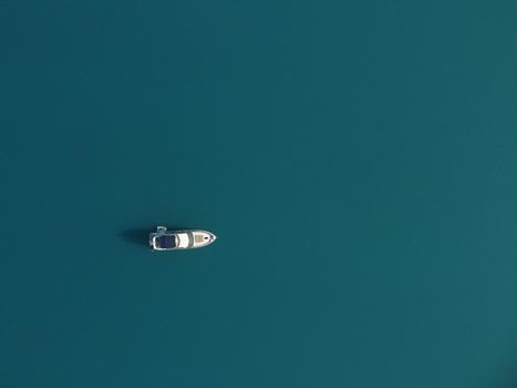 Aerial boat race. Luxury cruise trip. View from above of white boat on deep blue water. Aerial view of rich yacht sailing sea. Motor boat racing wave. Summer journey on luxury ship