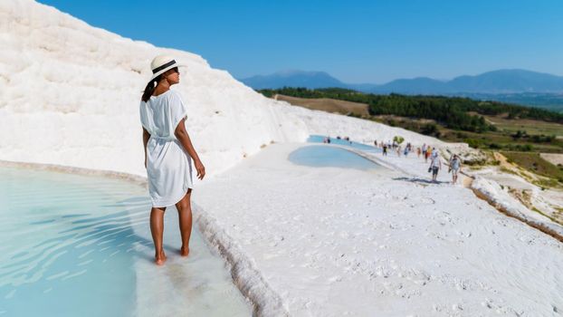 Natural travertine pools and terraces in Pamukkale. Cotton castle in southwestern Turkey, girl in white dress with hat natural pool Pamukkale Turkey