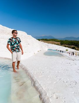 Natural travertine pools and terraces in Pamukkale. Cotton castle in southwestern Turkey,young men watching sunset at the natural pool Pamukkale Turkey