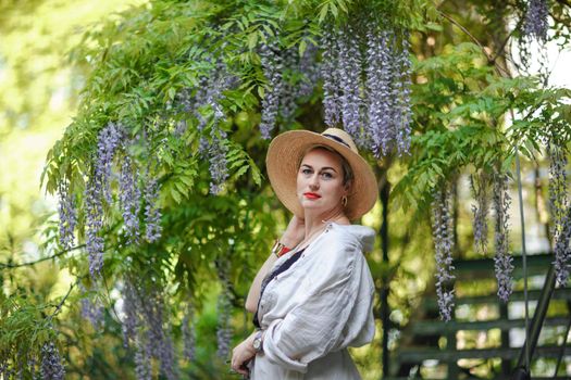 Thoughtful happy mature woman surrounded by chinese wisteria.