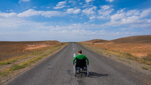 Woman in a wheelchair on a highway in the steppes