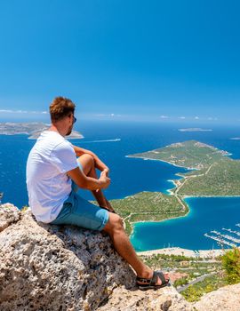 Kas turkey, Panoramic view from the mountain over the Kas Rivera, hiking up Lycian trail mountain of Kas Turkey. men looking out over ocean sitting on a rock