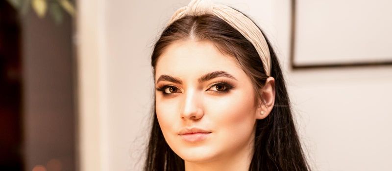 The fashionable young woman. Portrait of the beautiful female model with long hair and makeup. Beauty young caucasian woman with a hoop on her head