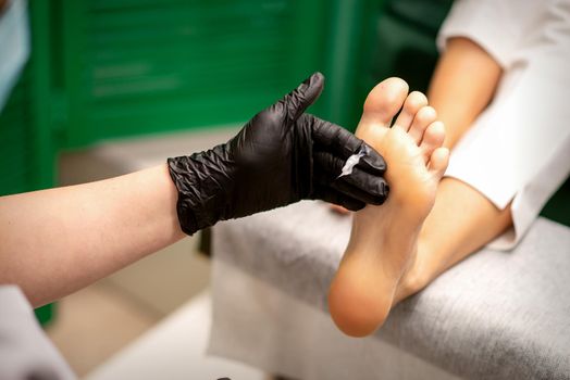 Manicure master applying cream on female client foot massage in a beauty salon