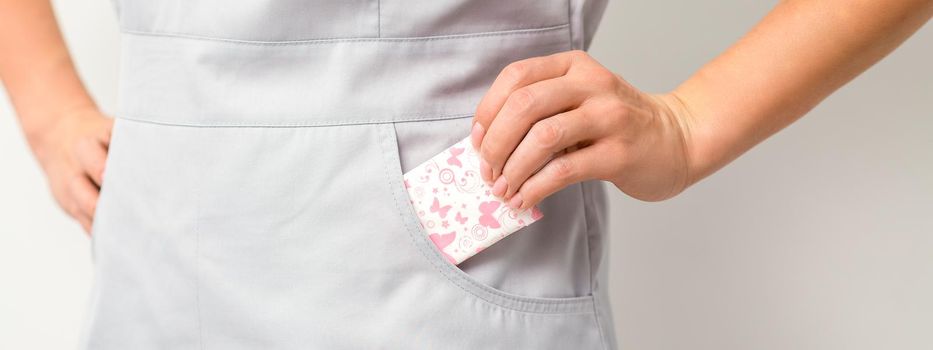 The female hand puts menstrual sanitary pads into her pocket, close up