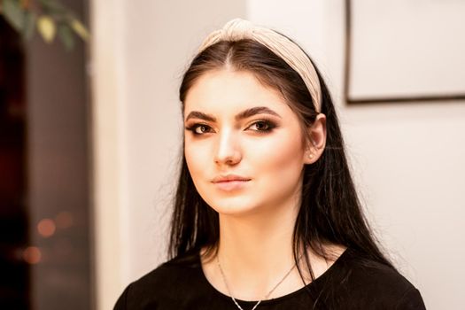 The fashionable young woman. Portrait of the beautiful female model with long hair and makeup. Beauty young caucasian woman with a hoop on her head