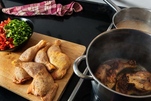 chicken fried in a pot, to cook it with the vegetables that are chopped on the plate on the wooden board, and the soup in the other pot