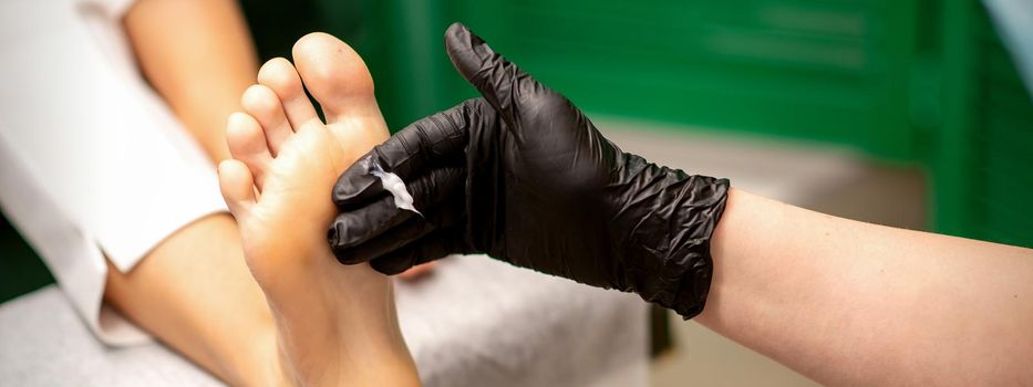 Manicure master applying cream on female client foot massage in a beauty salon