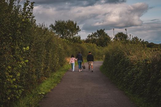 Family walking in path towards the woods. High quality photo