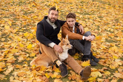 Father and son with a pet on a walk in the autumn park.