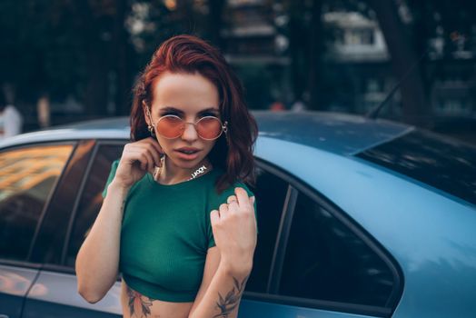 Young woman in glasses posing near car