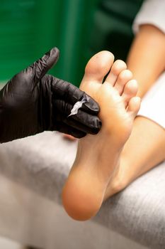 Manicure master applying cream on female client foot massage in a beauty salon