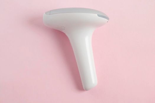 home modern laser epilator. Hair Remover offering Permanently Smooth Skin. Flash Epilator Laser on a pink background. Female blog concept. Photoepilator for home use. High quality photo