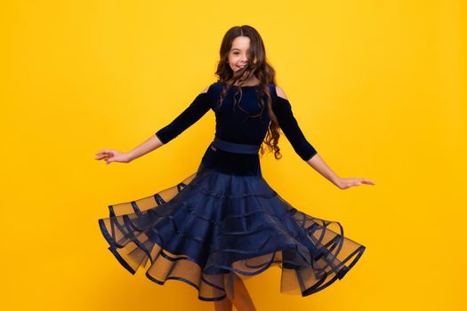 Happy face, positive and smiling emotions of teenager girl. Young graceful teenager child in fashion dress isolated on yellow background. Movement dress of young child teen girl