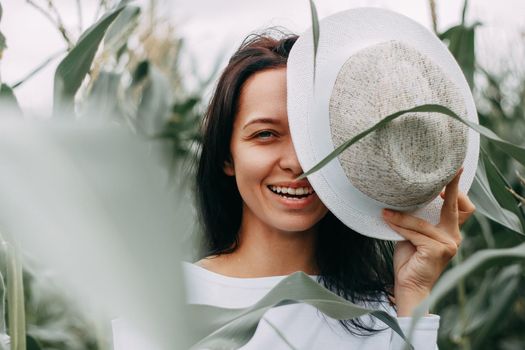 A brunette girl in a white dress in a cornfield. The concept of harvesting.
