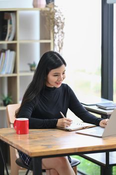 Portrait young woman designer with laptop computer while sitting in creative workplace.