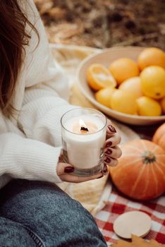 Girl holding aroma candle sitting on plaid