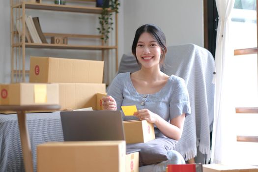 Shipping shopping online ,young start up small business owner writing address on cardboard box at workplace.small business entrepreneur SME or freelance asian woman working with box at home.