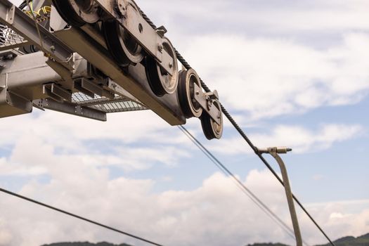 powerful metal wheel in a strong reliable mechanism on a mountain comfortable multi-colored lift in a mountain spruce and deciduous forest, against a cloudy sky