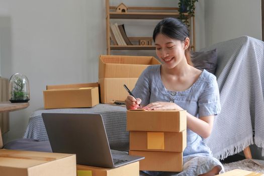 SME entrepreneur Small business entrepreneurs Online selling ideas,Happy Young Asian business owner work on computer and a boxs at home,delivery SME procurement package box deliver to customers,.