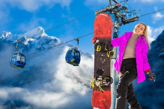 Back view of female snowboarder standing with snowboard in one hand and enjoying alpine mountain landscape - snowboarding concept.