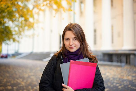 Beautiful student girl with folders and books going to classes in the morning, ready for a new day of education