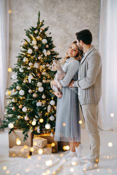 A happy couple in love - a man and a woman. A family in a bright New Year's interior with a Christmas tree.