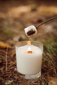 Roasting marshmallow on a candle in autumn forest. Autumn mood