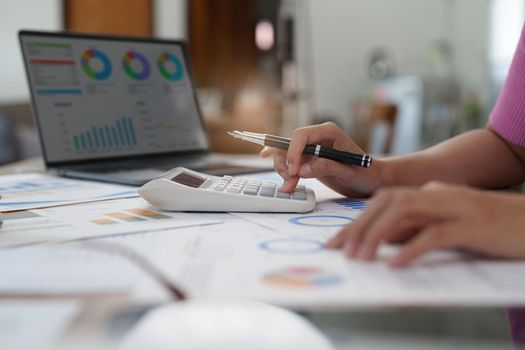 Business woman hand using calculator to calculate the company's financial results and budget. Account Audit Concept.