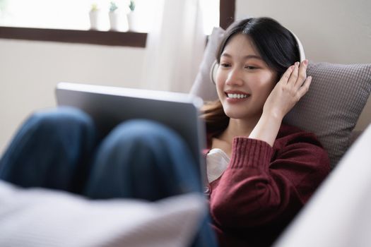 Attractive smiling young woman using tablet and listen music on sofa at home. lifestyle concept.