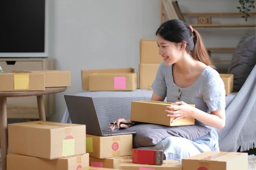 Shipping shopping online ,young start up small business owner writing address on cardboard box at workplace.small business entrepreneur SME or freelance asian woman working with box at home.