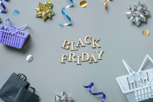 Black friday text with gifts, shopping baskets and bags and festive tinsel flat lay.
