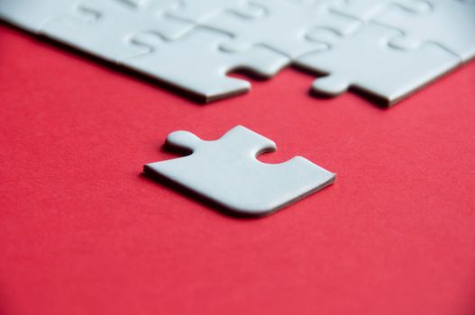 White jigsaw puzzle on red cover background with customizable space for text or idea. Copy space.