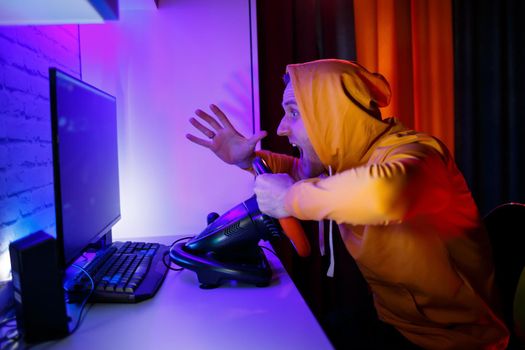 Male gamer playing racing games on the computer. He uses the steering wheel. Emotional game